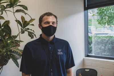 An employee wears a black mask and a dark blue housekeeping shirt.