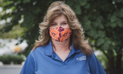 Susan Hypes, Housekeeper, standing outside wearing a VT orange and maroon mask and a blue housekeeping shirt.