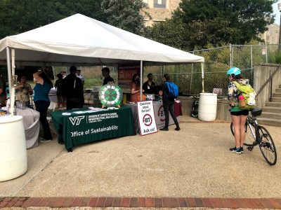 Office of Sustainability table at the Sustainable Transportation Fair. A student with a bike waits to talk to office of sustainability graduate assistants about sustainability on campus.