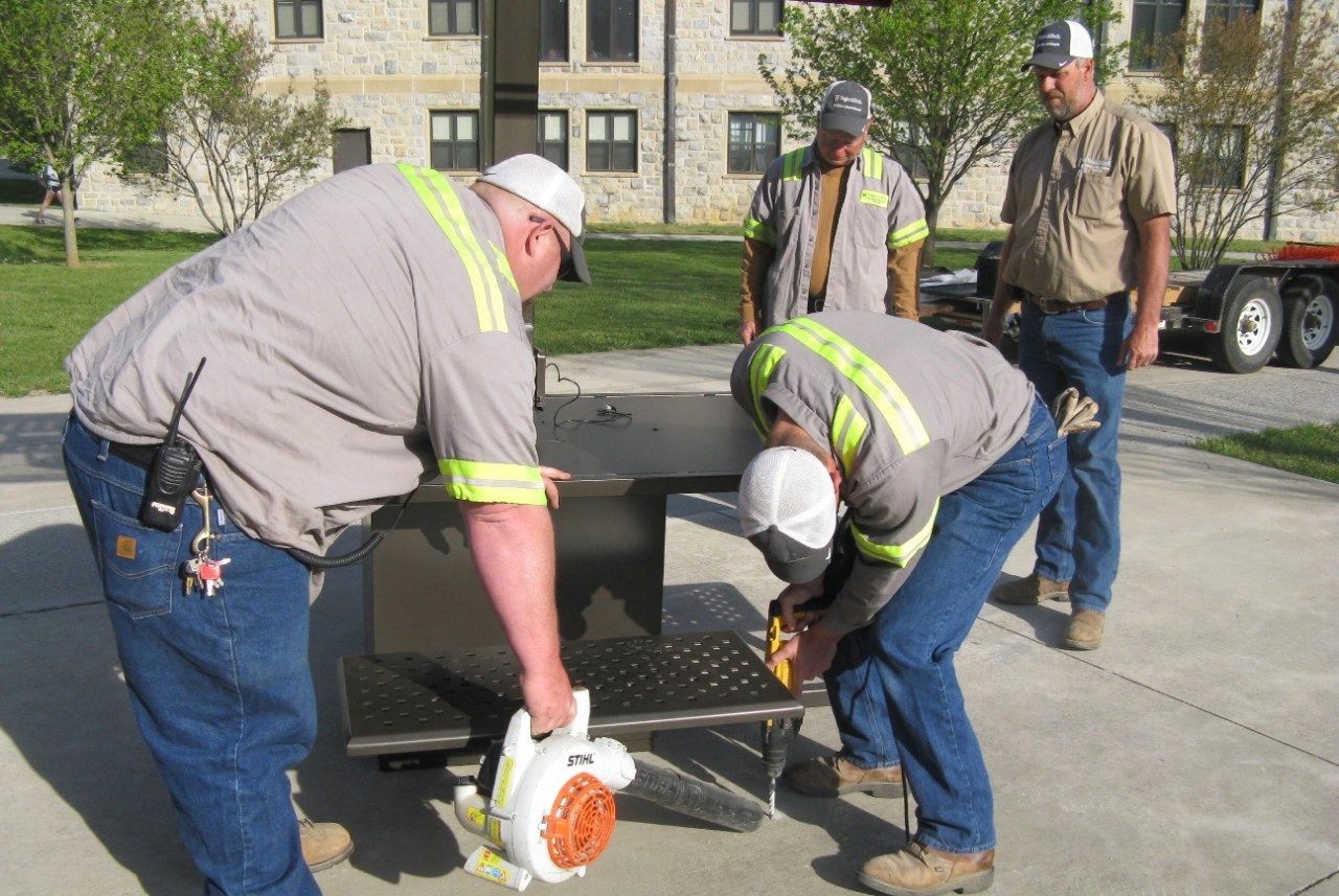 Facility employees drilling a hole in concrete to secure the solar table.