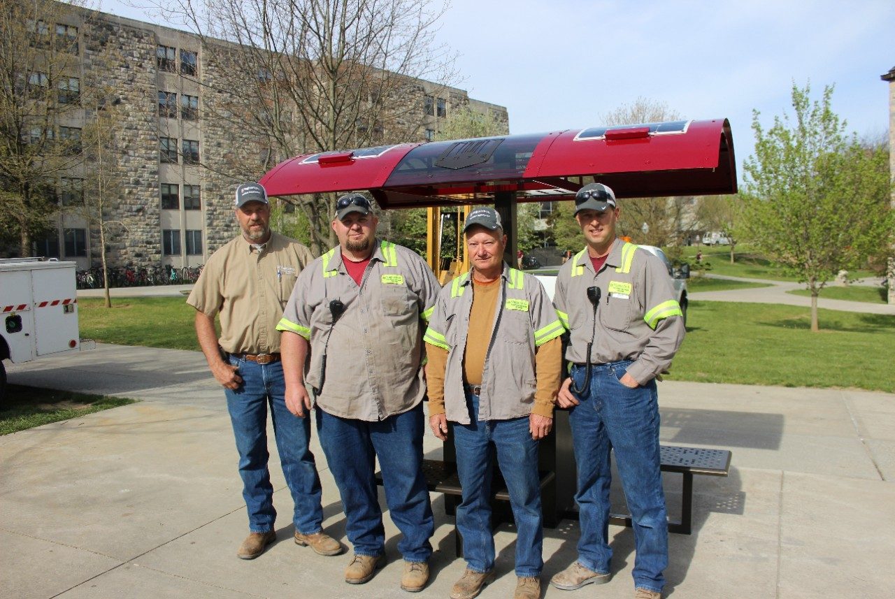 Facilities employees posing in front of the installed solar table.