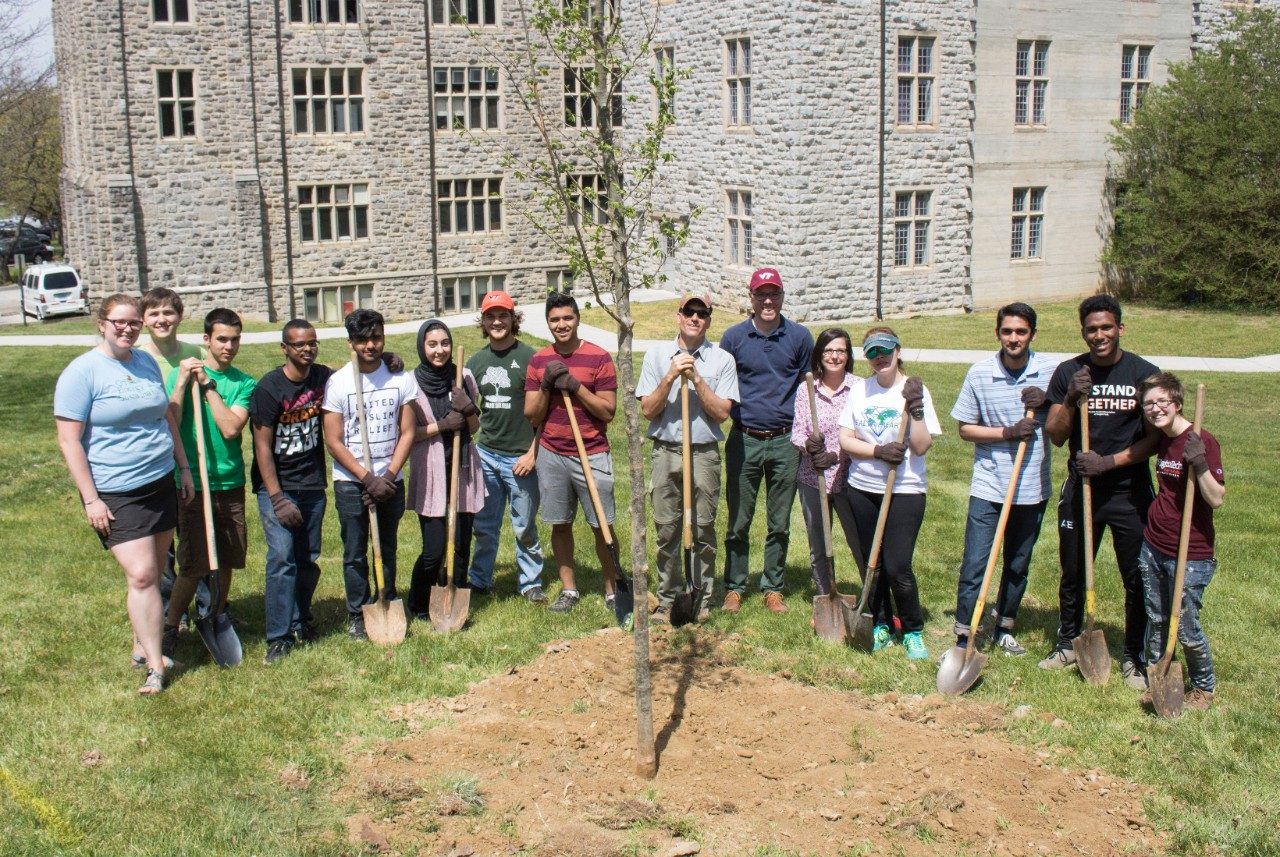 Students and employees posing behind a newly planted sapling.