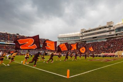 People carry flags that spell out Hokies before the start of the 2023 homecoming football game