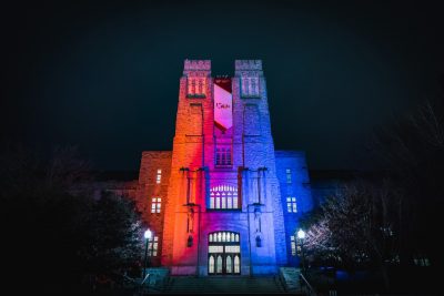 Photo shows Burruss Hall illuminated with orange and blue
