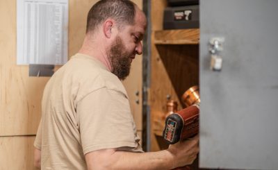 A man holds a power tool and is getting ready to fix something inside a cabinet