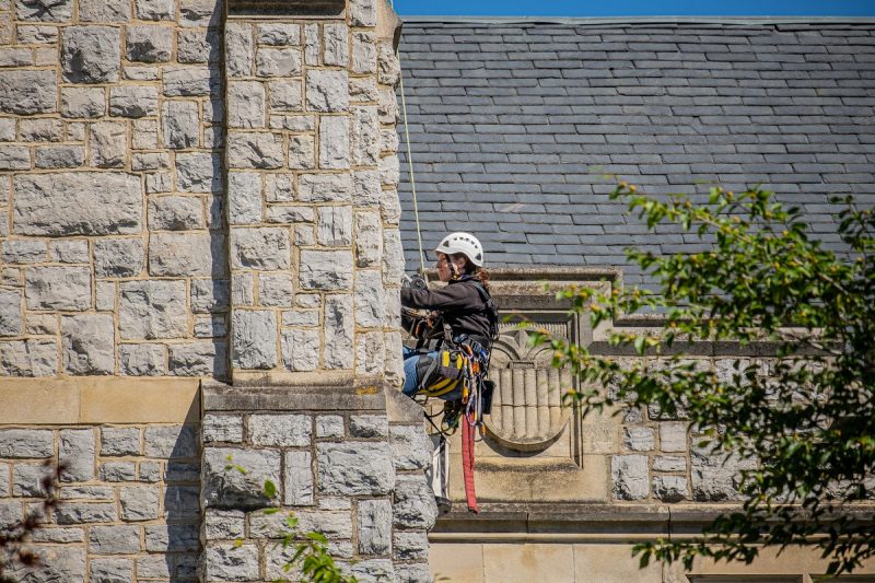 employee repelling down side of hokie stone building