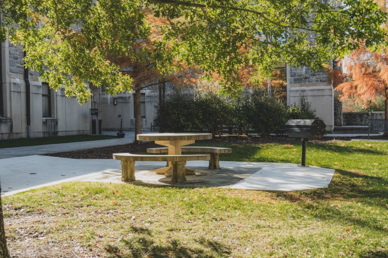 Concrete table and seating area outside the Smith Career Center on a sunny autumn day, with new larger concrete pads surrounding it so that it is accessible to all.
