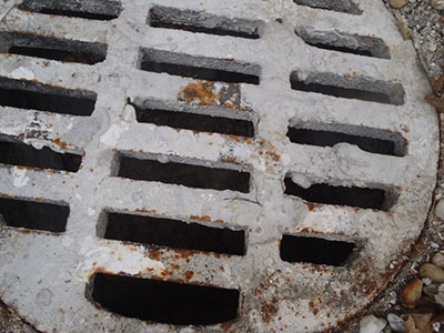 A drain cover corroded by pollutants in the water.