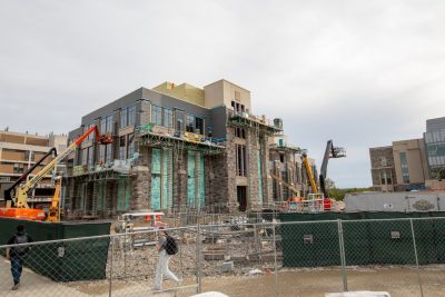 A view of Hitt Hall under construction. There are several cranes along the outside walls of the structure. There is Hokie Stone about halfway up the exterior.