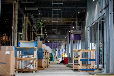 The inside of Hitt Hall while under construction. There is purple drywall, exposed metal framed walls, and empty wooden crates.