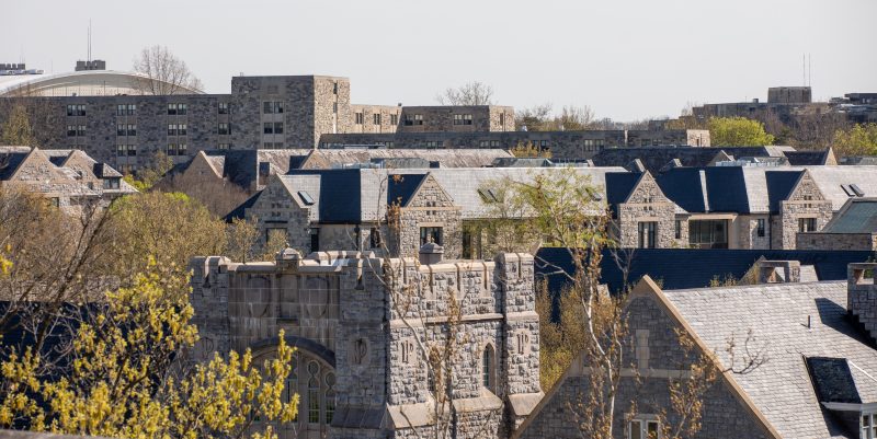 A rooftop view of various campus buildings with blossoming spring trees