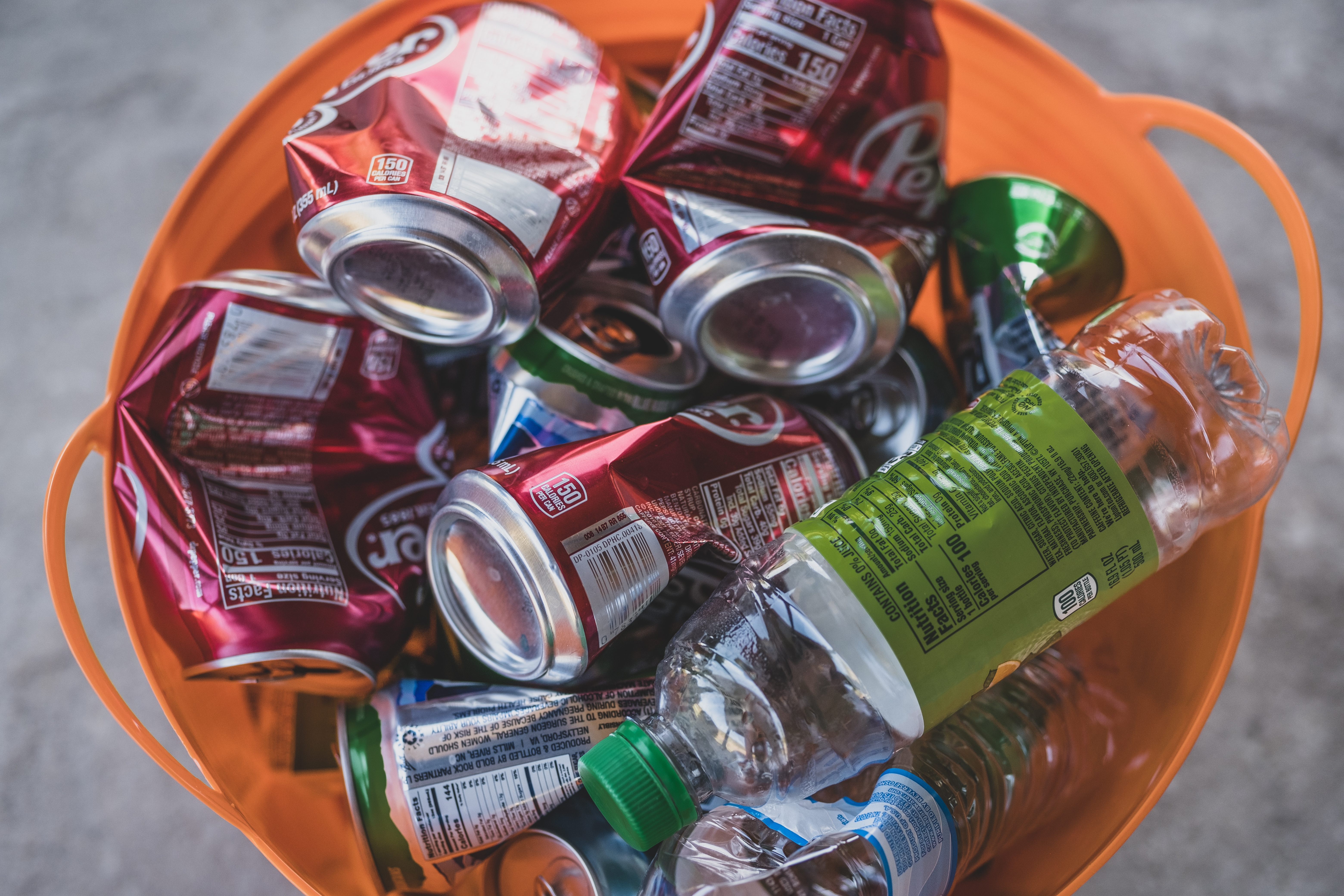 Orange plastic bin with empty plastic bottles and aluminum cans