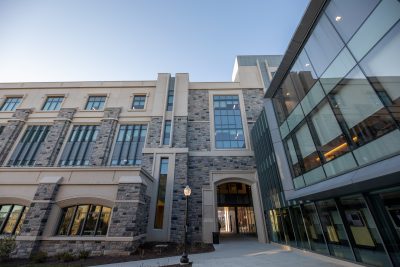 A new building on campus featuring Hokie Stone and shiny clean windows. Photo is taken at an angle pointing upward.