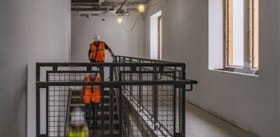 A stairwell inside a construction project with lights and people walking down the stairs in a blur of motion.