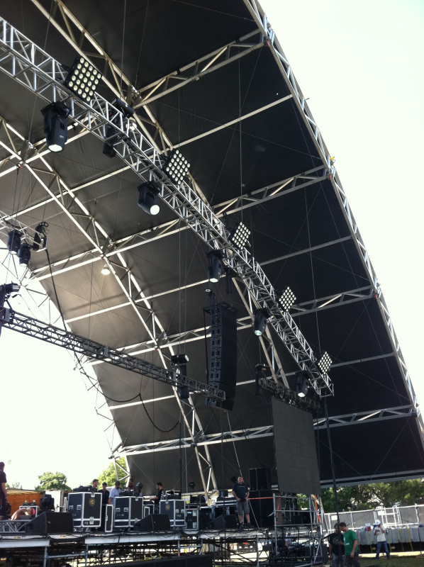 Arched overhead stage lighting structure with light boxes and spotlights equally spaced along the top.