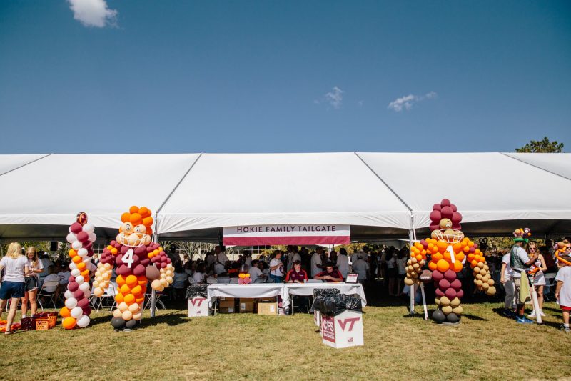 Hokie Family Game Day large tent with people, orange and maroon balloons, and two football players made from balloons at the tent entrance.