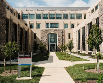 Grey Hokie Stone, precast concrete, and glass exterior of the Data and Decision Sciences Building with a courtyard with several small trees and benches