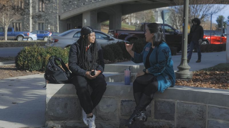 Colleagues discuss parts of their day as they sit near Torgerson Bridge.