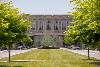 Grey Hokie Stone Torgersen Bridge surrounded by green trees. 