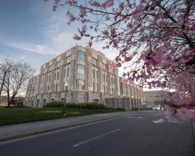 Grey Hokie Stone Goodwin Hall surrounded by blossoming pink trees