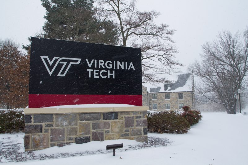 A black and maroon sign with a Virginia Tech logo on it surrounded by winter snow