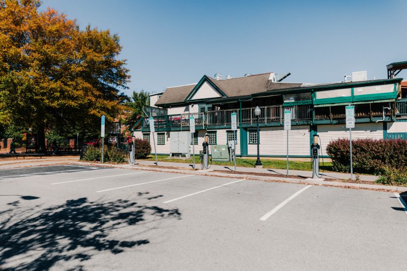Electric vehicle charging stations in a parking lot next to a white and green building