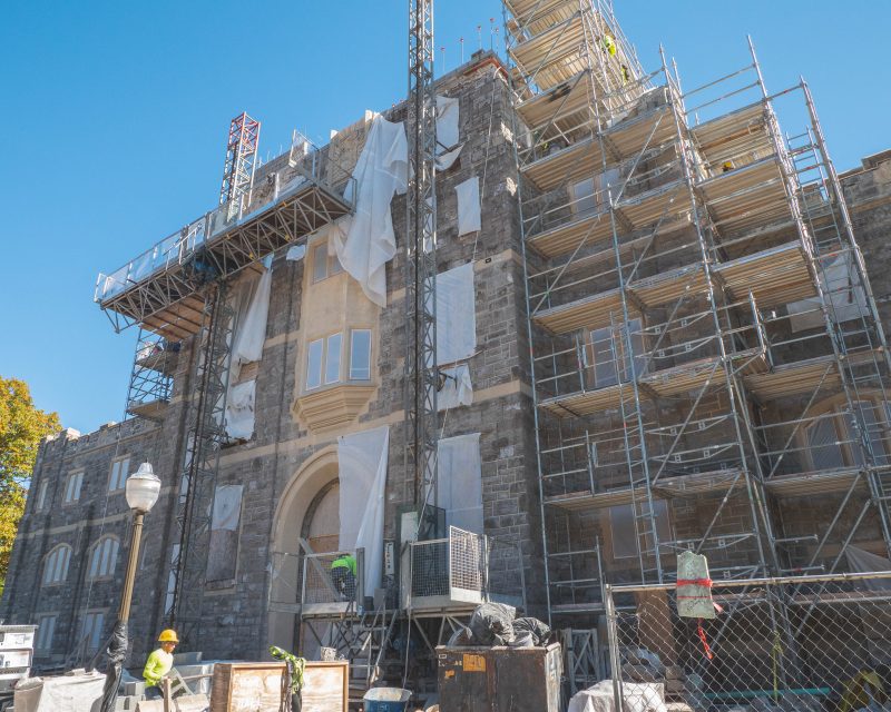 Exterior of grey Hokie Stone War Memorial Hall with scaffolding covering it