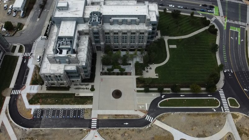 Aerial view of a road sloping around grey hokie stone Goodwin Hall