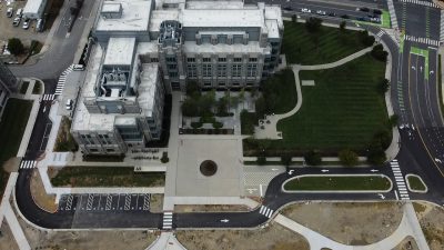 Aerial view of a road sloping around grey hokie stone Goodwin Hall