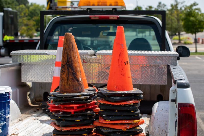 Many orange cones stacked on top of one another in the back of a white pickup truck